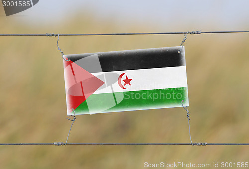 Image of Border fence - Old plastic sign with a flag