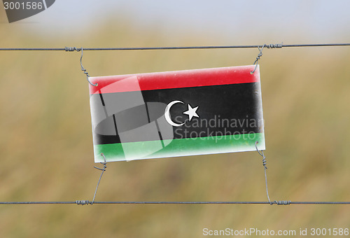 Image of Border fence - Old plastic sign with a flag