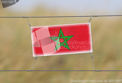 Image of Border fence - Old plastic sign with a flag