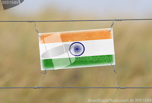 Image of Border fence - Old plastic sign with a flag