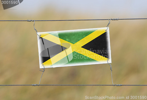 Image of Border fence - Old plastic sign with a flag