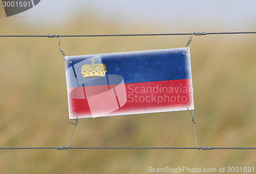 Image of Border fence - Old plastic sign with a flag