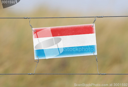 Image of Border fence - Old plastic sign with a flag