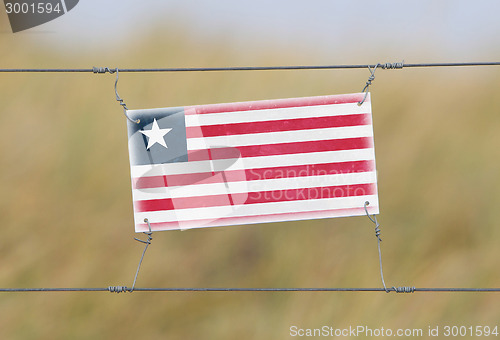 Image of Border fence - Old plastic sign with a flag