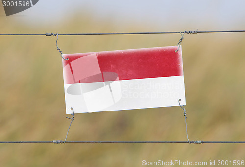 Image of Border fence - Old plastic sign with a flag