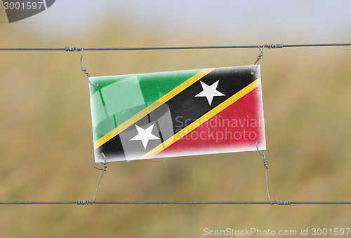 Image of Border fence - Old plastic sign with a flag