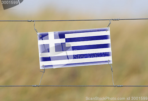 Image of Border fence - Old plastic sign with a flag