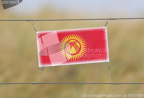 Image of Border fence - Old plastic sign with a flag