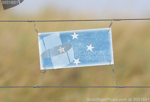 Image of Border fence - Old plastic sign with a flag