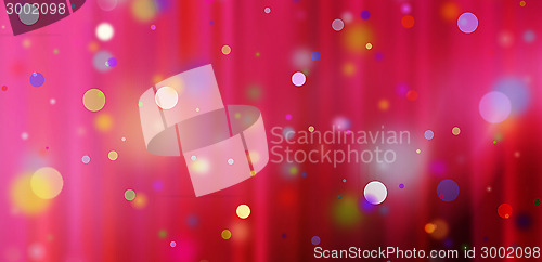 Image of confetti against a red blurred curtain background