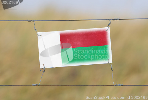 Image of Border fence - Old plastic sign with a flag