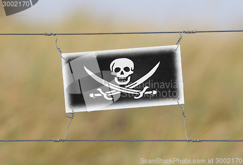 Image of Border fence - Old plastic sign with a flag