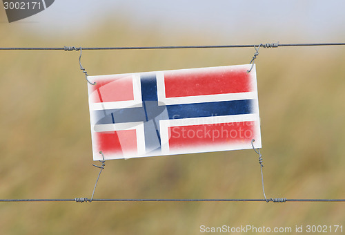 Image of Border fence - Old plastic sign with a flag