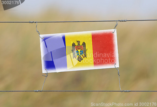 Image of Border fence - Old plastic sign with a flag