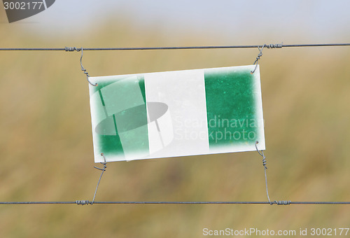 Image of Border fence - Old plastic sign with a flag