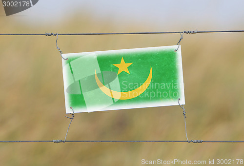 Image of Border fence - Old plastic sign with a flag