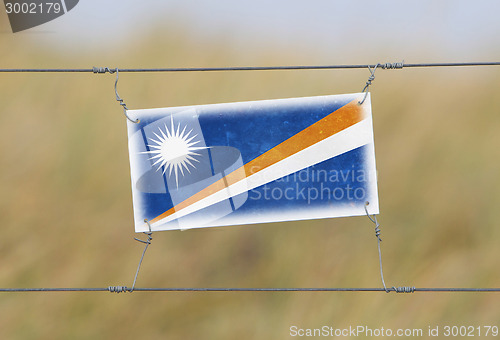 Image of Border fence - Old plastic sign with a flag