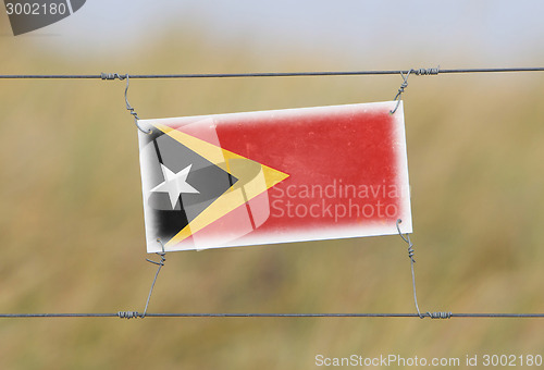 Image of Border fence - Old plastic sign with a flag