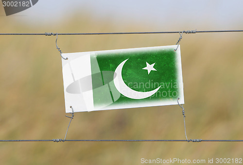 Image of Border fence - Old plastic sign with a flag