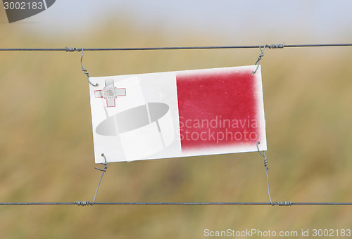 Image of Border fence - Old plastic sign with a flag