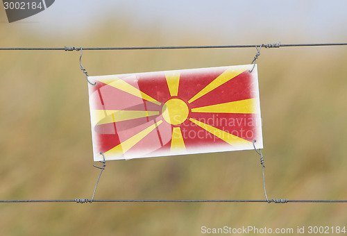 Image of Border fence - Old plastic sign with a flag