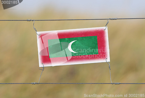 Image of Border fence - Old plastic sign with a flag