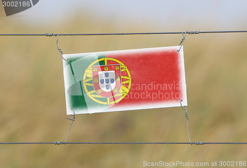 Image of Border fence - Old plastic sign with a flag