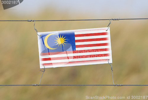 Image of Border fence - Old plastic sign with a flag