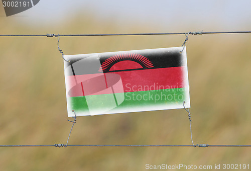 Image of Border fence - Old plastic sign with a flag