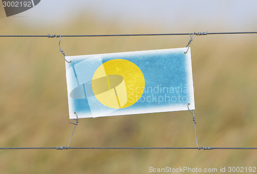 Image of Border fence - Old plastic sign with a flag