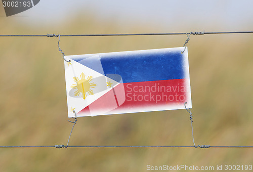 Image of Border fence - Old plastic sign with a flag