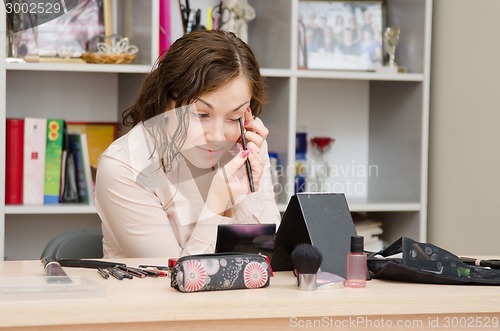 Image of girl at work in the office paint eyelashes