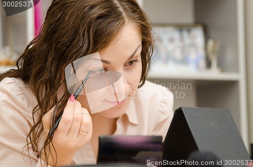 Image of Office girl paints her eyebrows at work