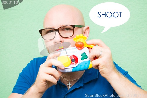 Image of Young man taking photo with toy camera