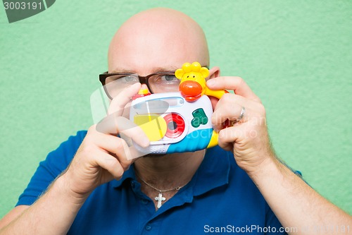 Image of Young man taking photo with toy camera