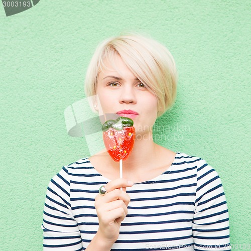 Image of Young sexy woman sucking lollipop. 