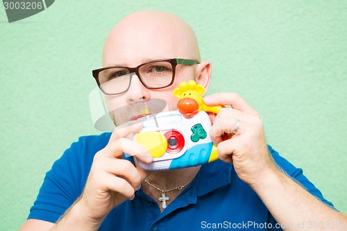 Image of Young man taking photo with toy camera