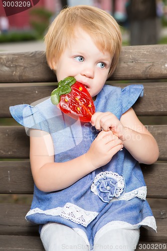 Image of Beautiful little girl holding strawberry shaped lollipop