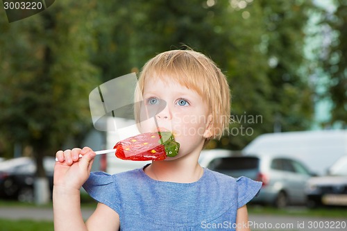 Image of Beautiful little girl holding strawberry shaped lollipop