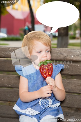 Image of Beautiful little girl holding strawberry shaped lollipop