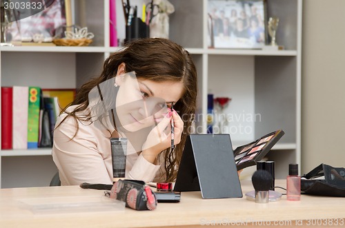 Image of employee paints her eyebrows at work