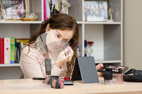 Image of Office worker paints her eyebrows at work