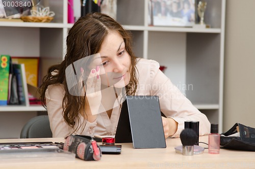 Image of Girl puts foundation on face at work