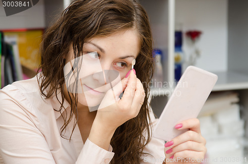 Image of Girl puts shadow on eyelids, look in mirror