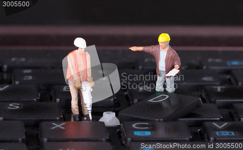 Image of Miniature workers with drill working on keyboard