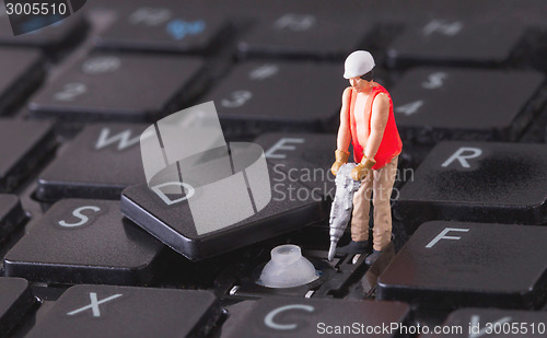 Image of Miniature worker with drill working on keyboard