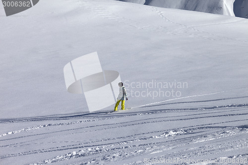 Image of Snowboarder downhill on off piste slope with newly-fallen snow