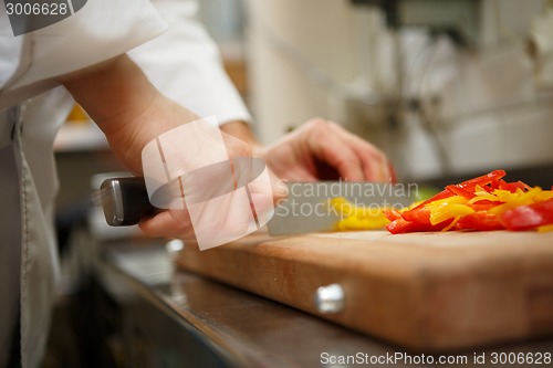 Image of closeup on hands cutting yellow pepper