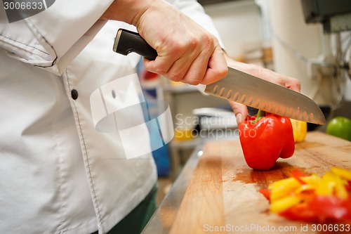 Image of closeup on hands cutting yellow pepper