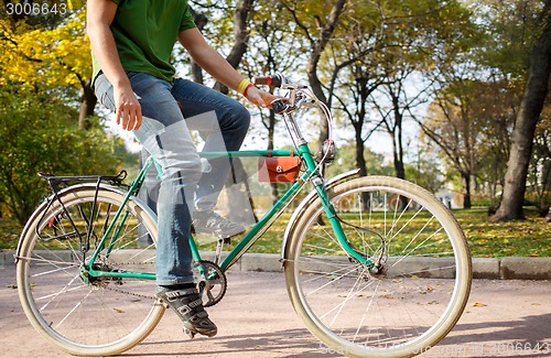 Image of Close-up of young man riding bicycle in park